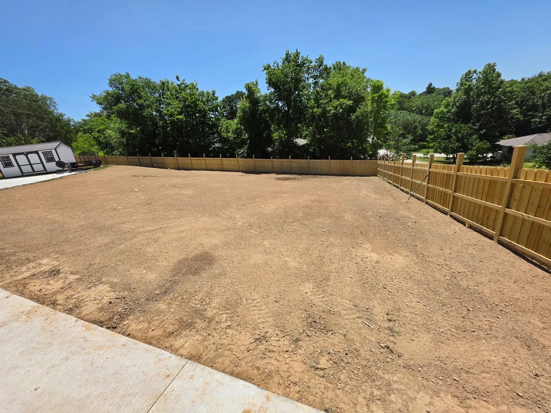 Before photo of an uneven backyard area with patchy grass before hardscape work