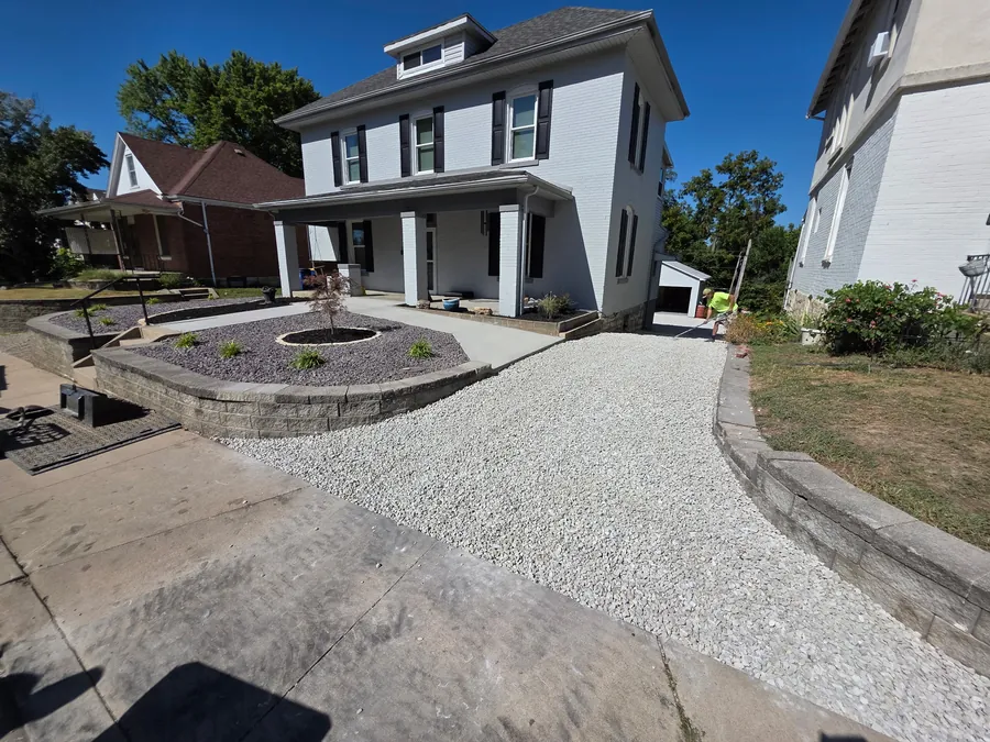 Front driveway and gravel landscape bed with a small round firepit area