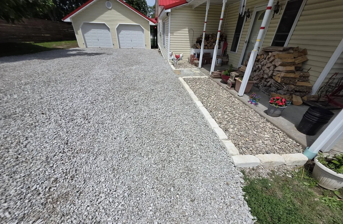 After photo of a widened gravel driveway with fresh rock, flagstone walkway, and clean edging